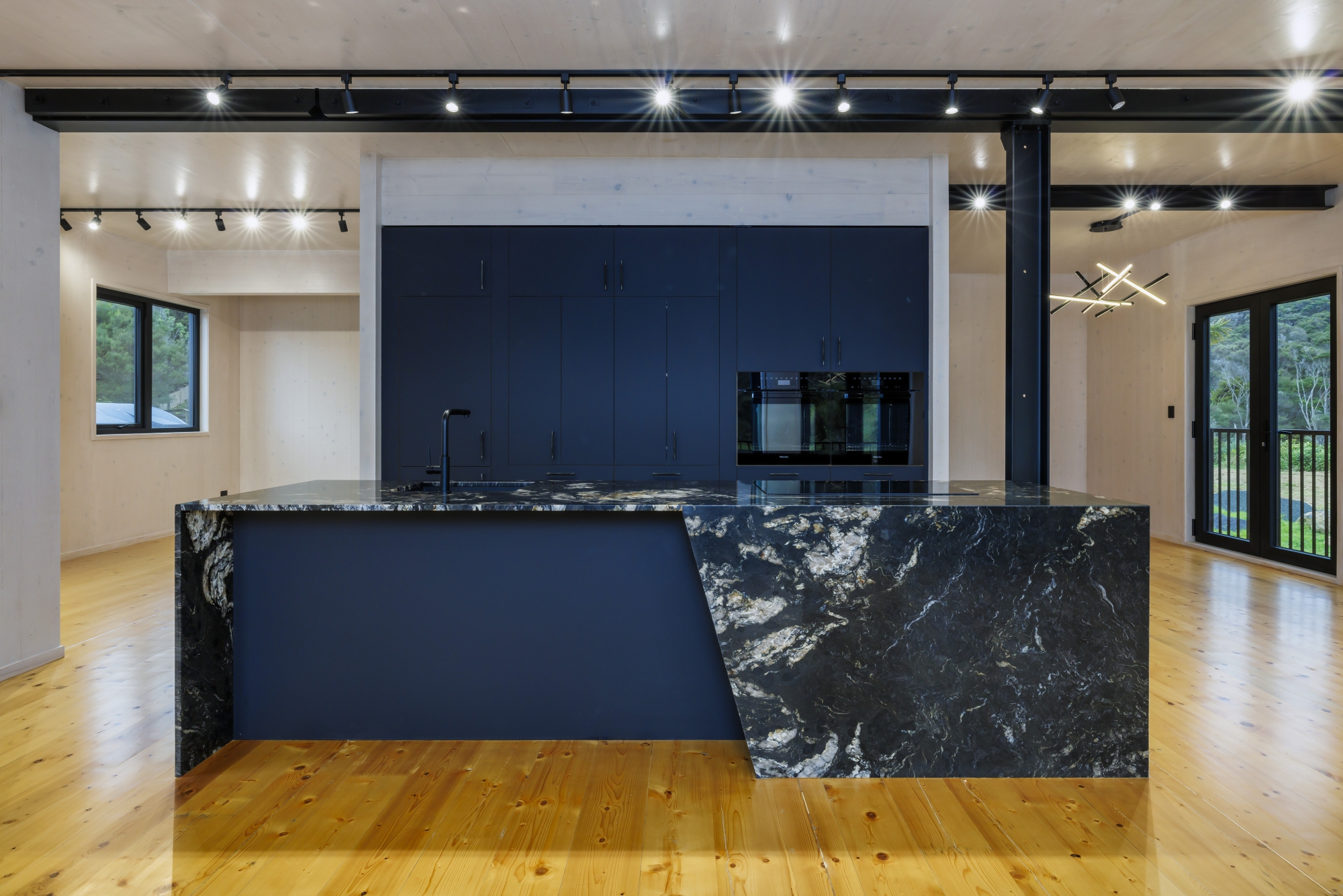 The Tūī — full kitchen wide shot showing the living connection and bush views