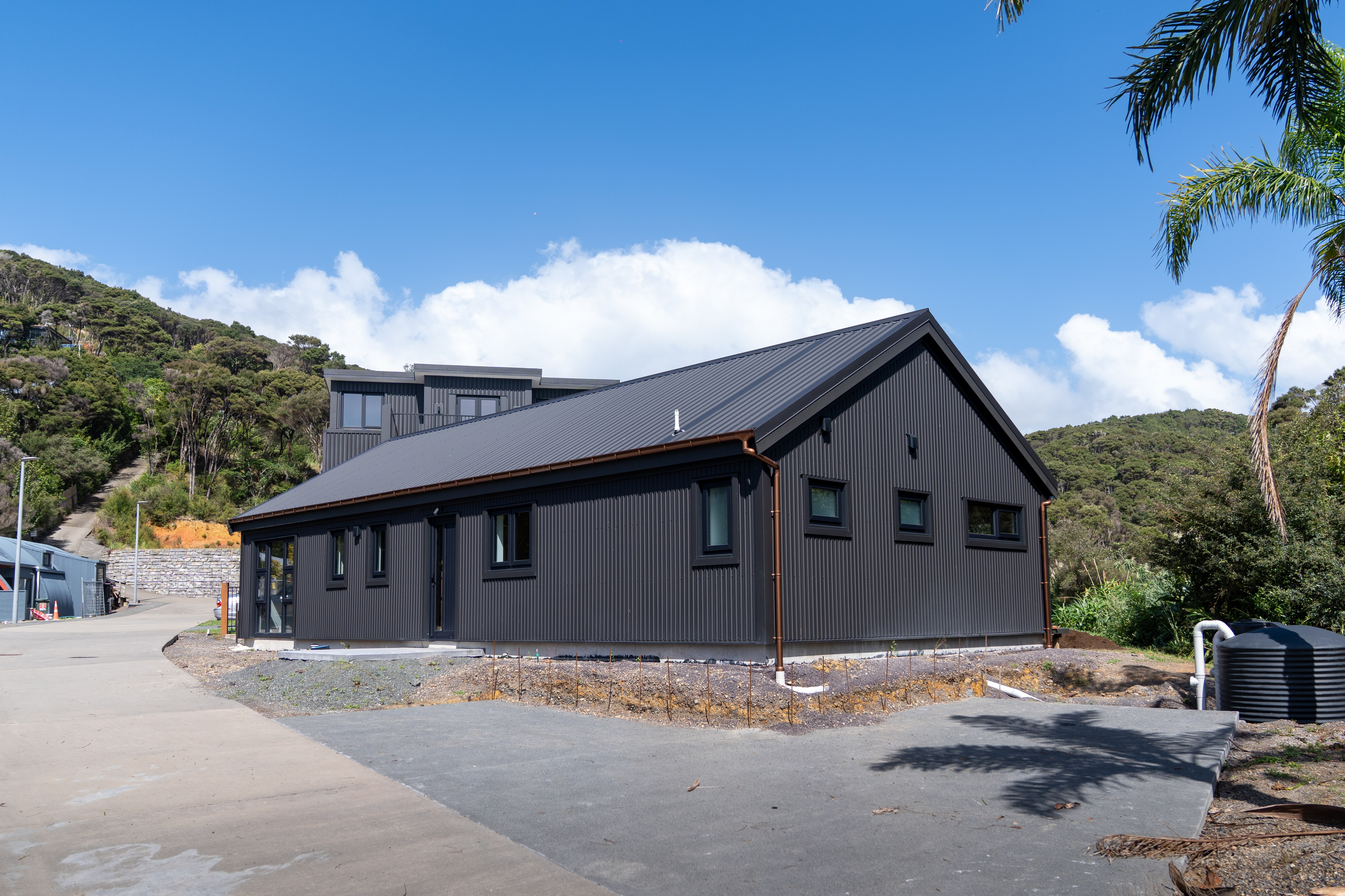 The Kauri — a single-storey solid timber home on a green lawn with mature trees behind